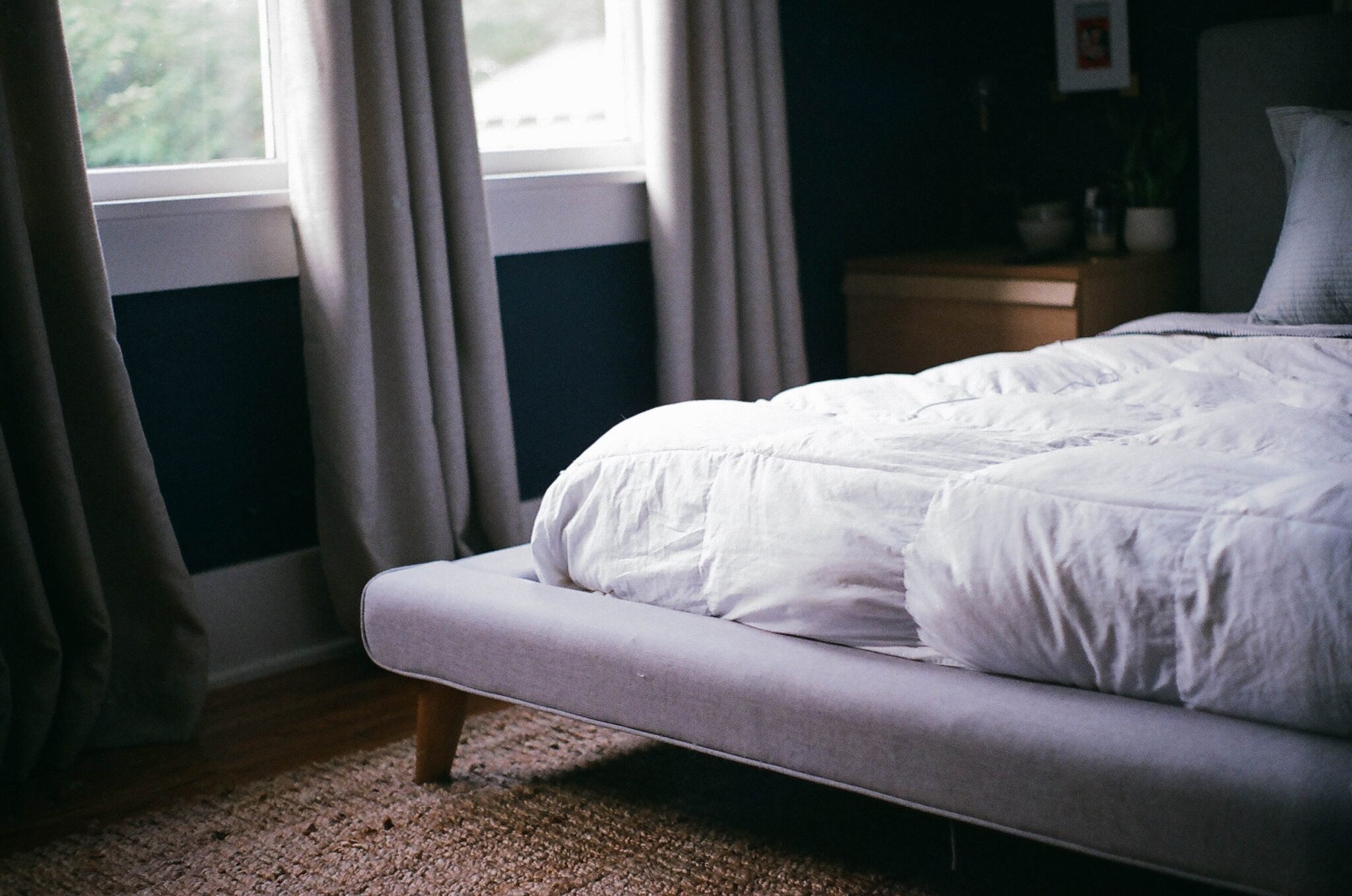 Apartment bedroom interior with bed, furnishings, and window allowing natural light