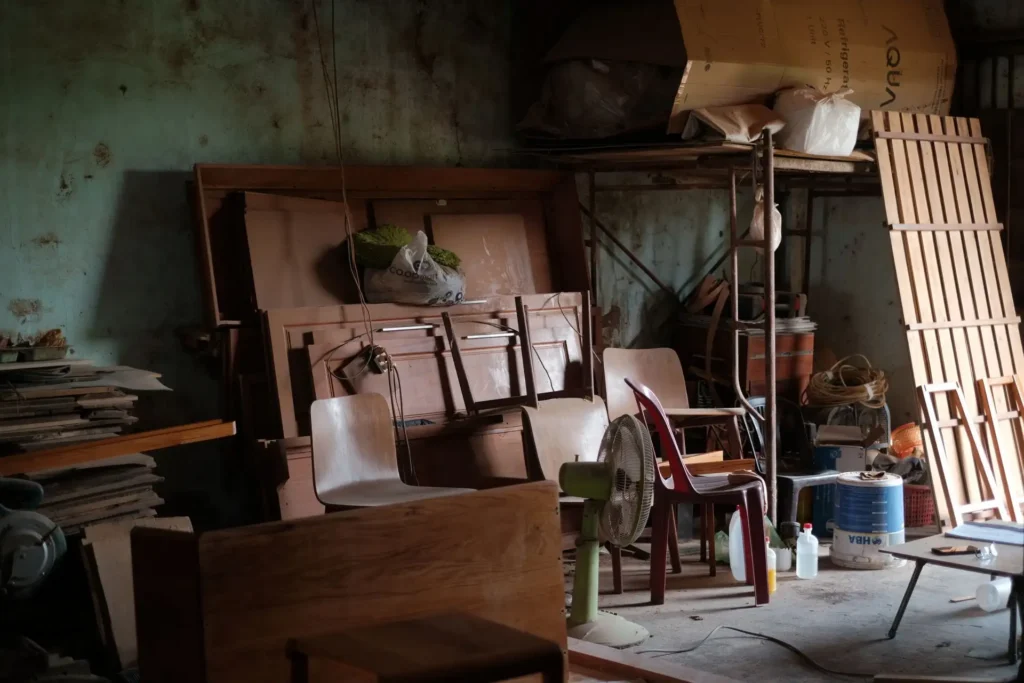 A cluttered basement filled with wooden furniture, tools, and various items.
