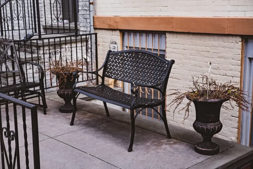 A stylish outdoor terrace featuring a decorative metal bench and potted plants, perfect for urban relaxation.