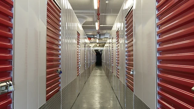 Interior hallway of Moishe's Self Storage facility with red storage unit doors lining both sides