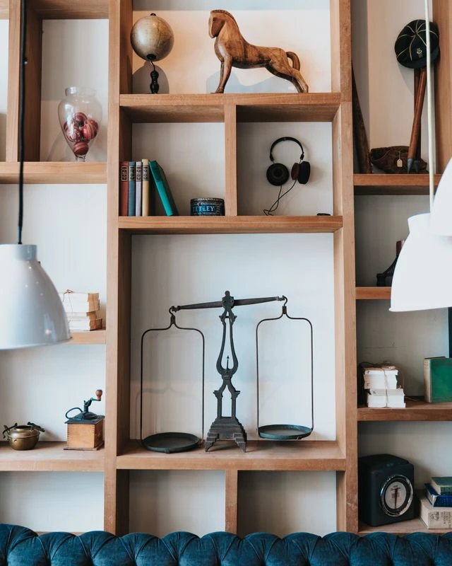 Vertical storage wall shelves in a small apartment holding an antique scale, horse statue, books, and coffee grinder